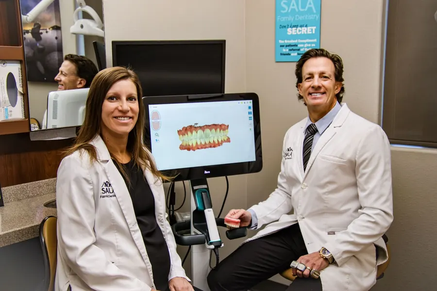 Dr. Christina Knapp and Dr. Jason Sala beside a digital scan of a patient's teeth.