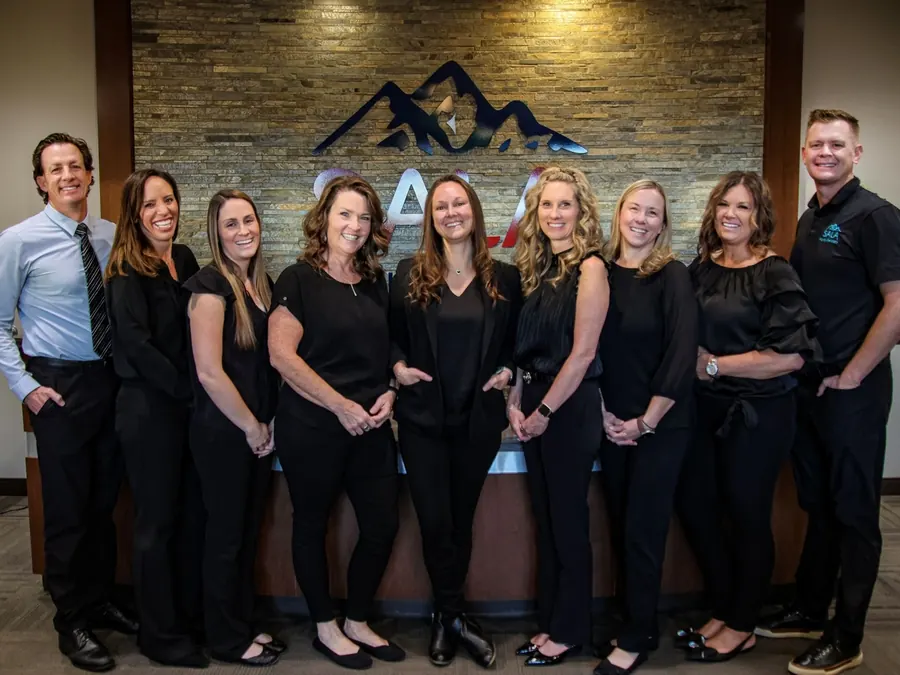 Part of the Sala Family Dentistry team at the front desk, with the SALA sign behind them.
