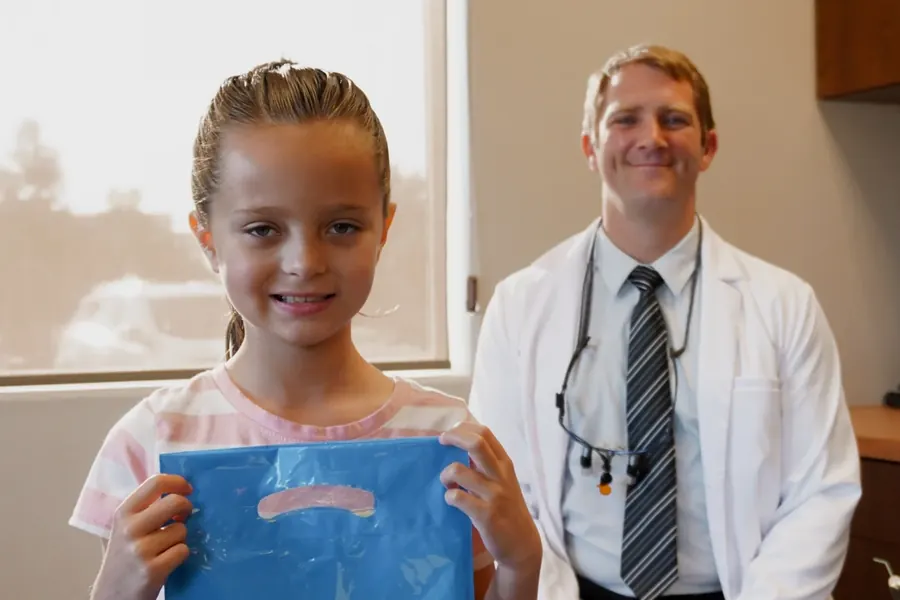 Dr. Jeff with a young patient holding her Sala goody bag.